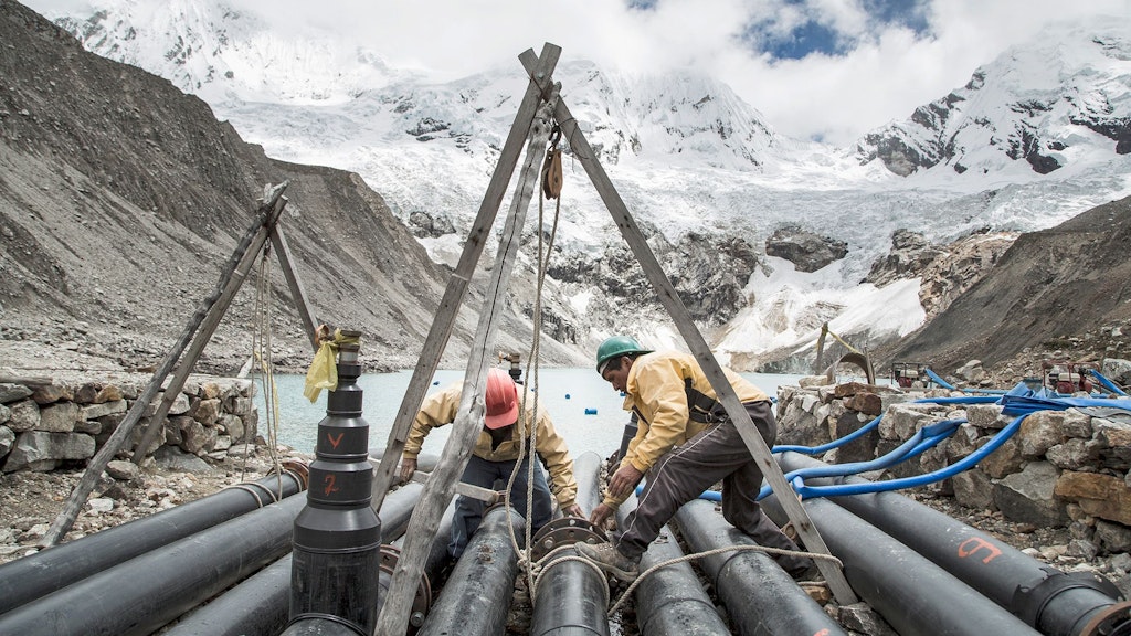 People working on drainage tubes in glacial lake