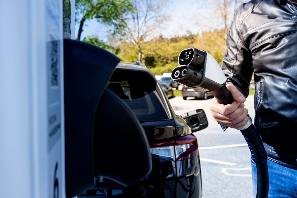 Man takes charging plug for electric vehicle from the charging station